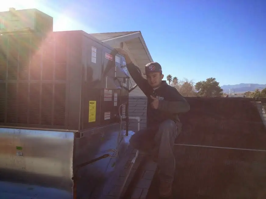 HVAC technician performing Air Duct Cleaning on a rooftop unit in Opelousas